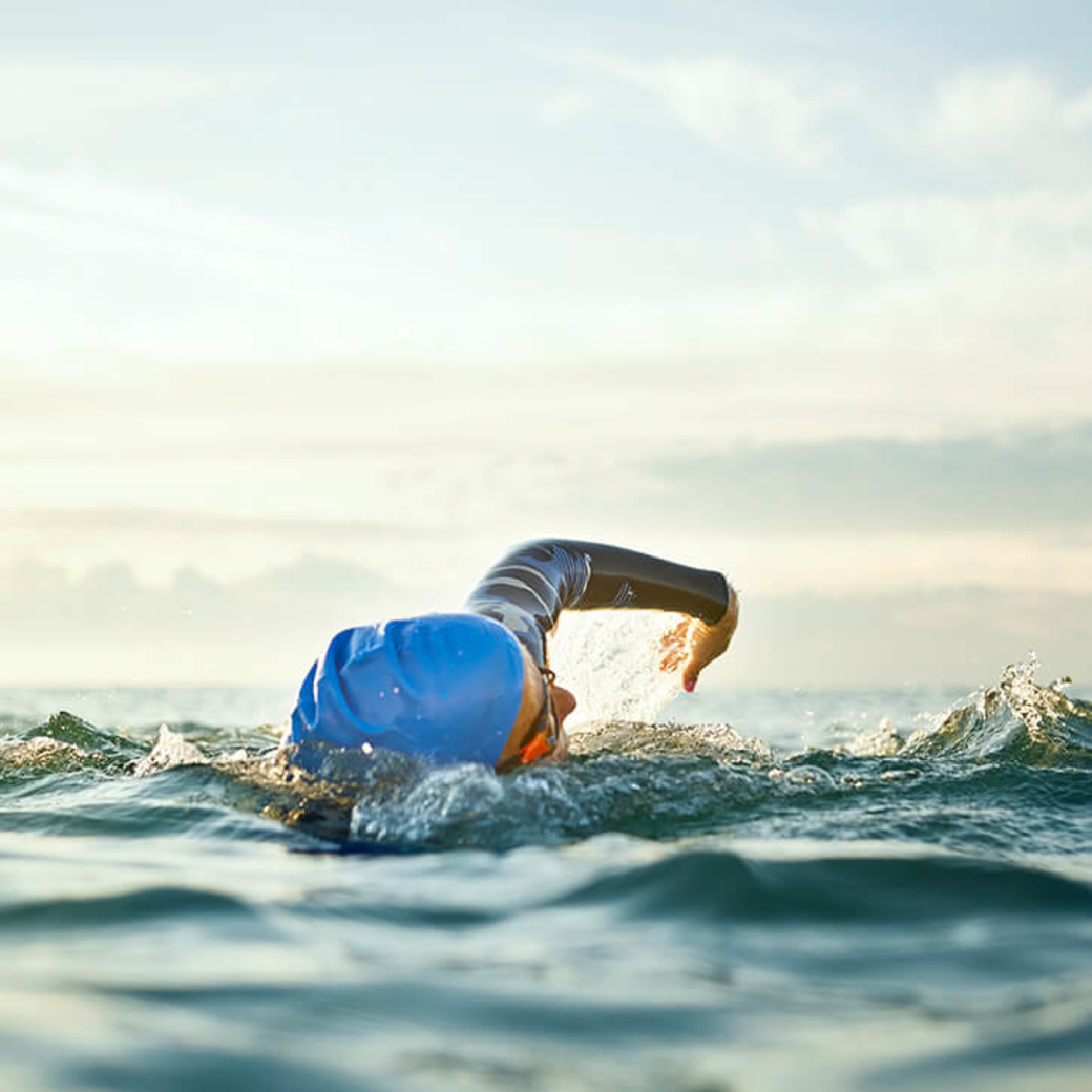 Frau schwimmt im Meer, um Gelenkschmerzen beim Sport zu vermeiden.